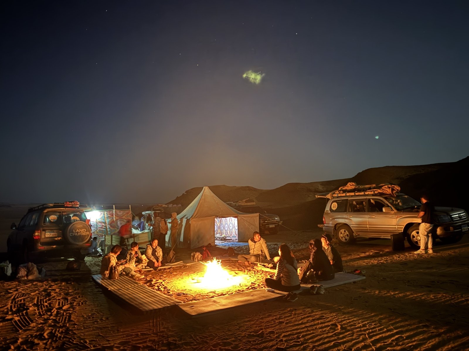 Travelers enjoying a desert camp beside a glowing fire