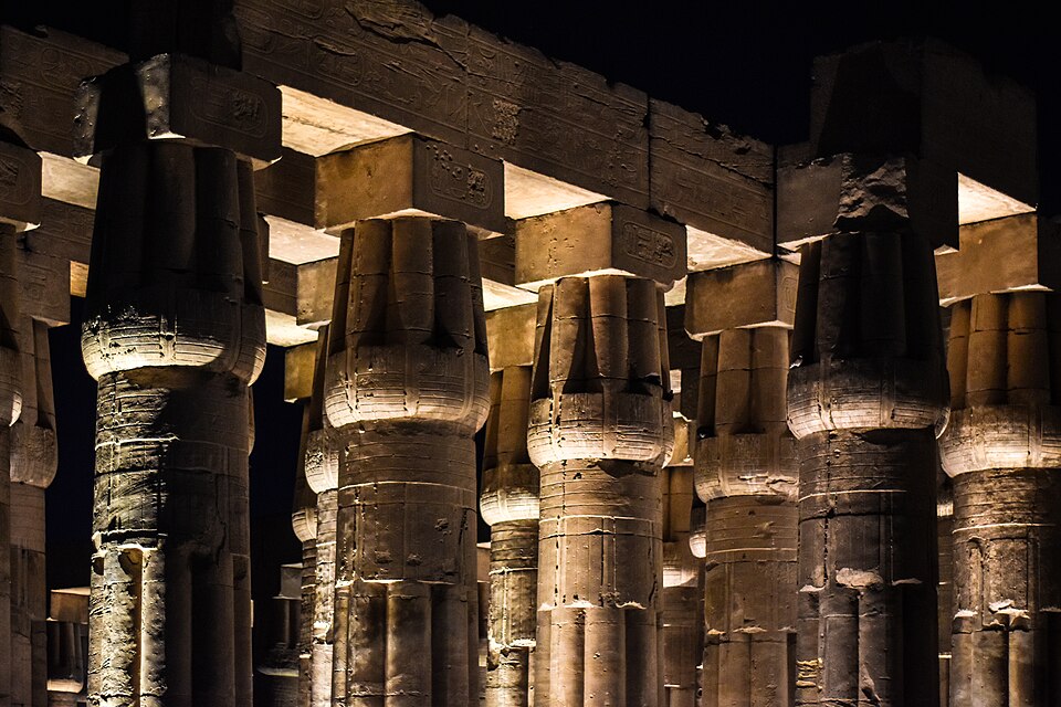 Illuminated columns and statues inside Luxor Temple at night